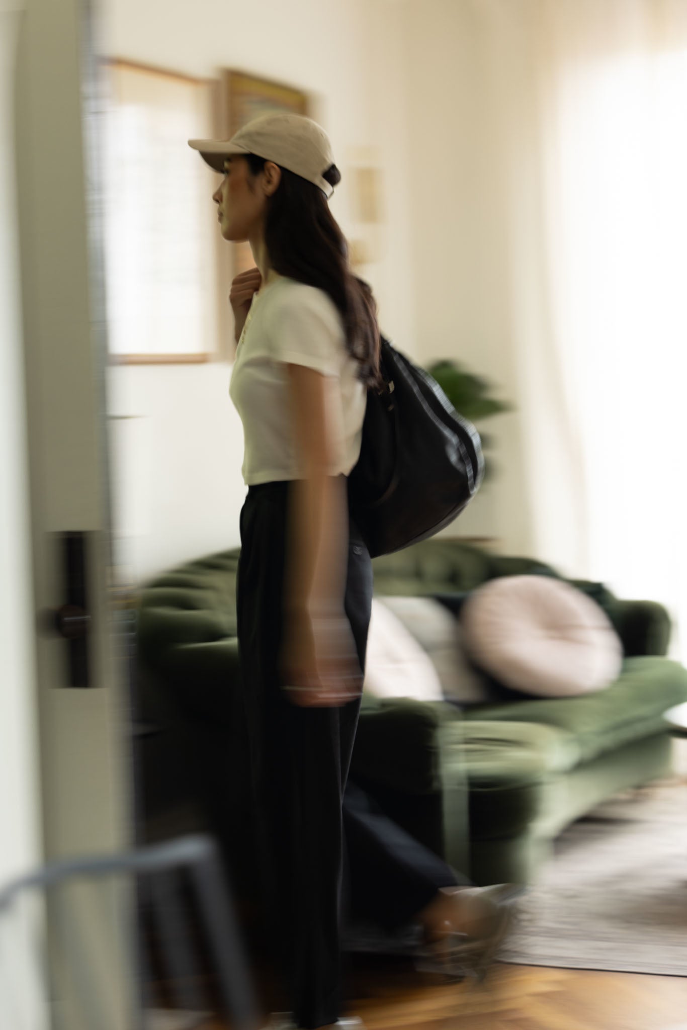 Model Alana in AB Dad Hat in Khaki, Trial Trouser in Black, and white tee walking out the door for morning errands