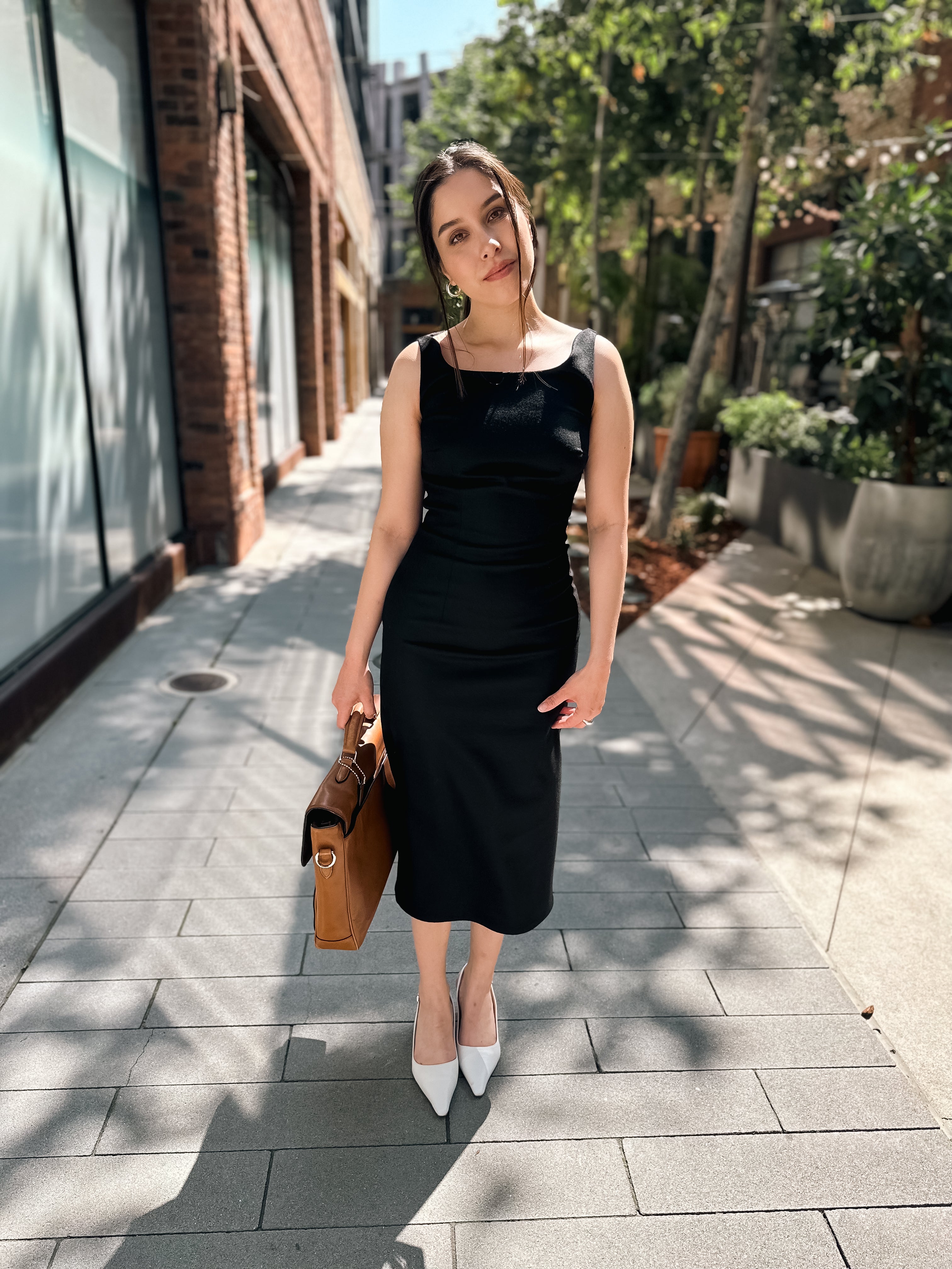Carol in Black 90's Midi Dress with briefcase and white slingback kitten heels 