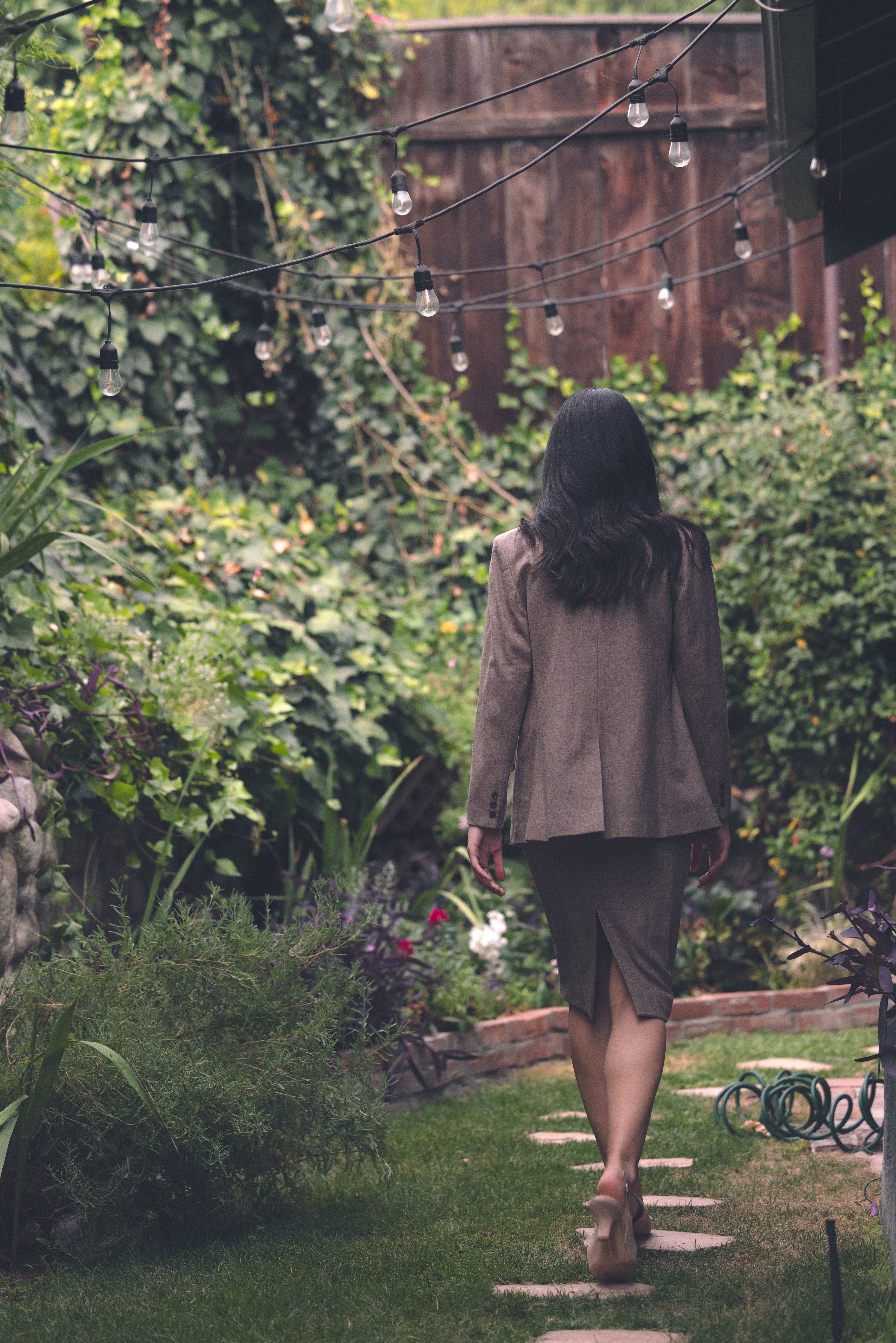 Back view of Alana in garden in 90's Midi and Court Jacket in Coffee 
