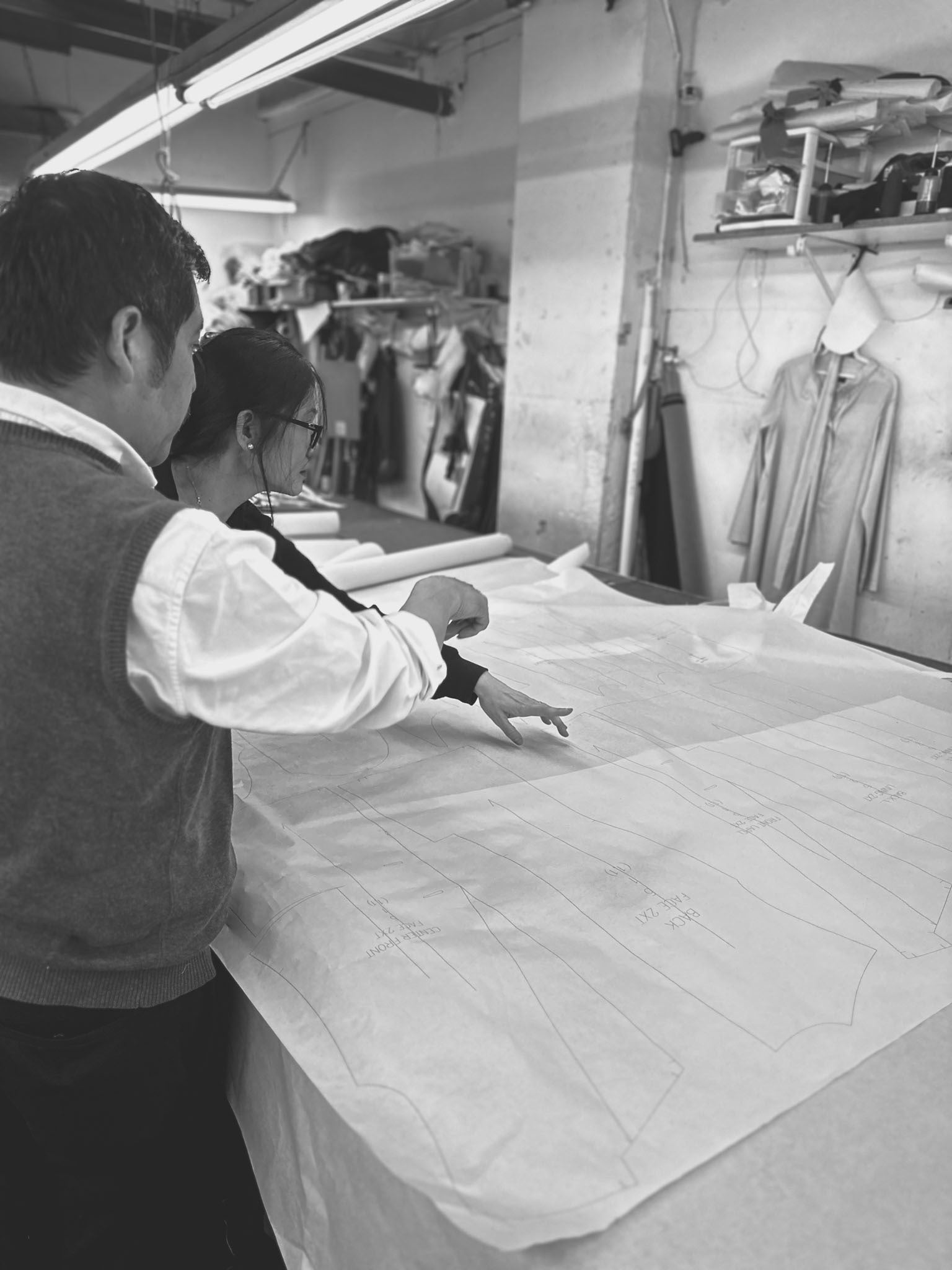 ALPHA BRAVA's pattern maker and material cutter at factory going over suit patterns in NYC